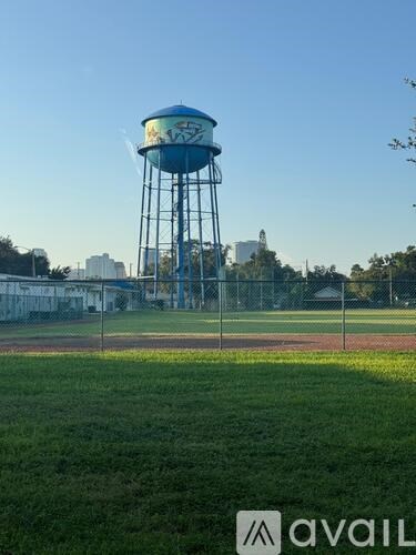 A large blue water tower stands in the middle of a grassy field.
