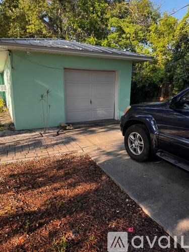 A black truck is parked in front of a green house.