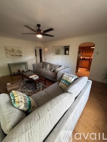 A living room with a grey couch and a ceiling fan.