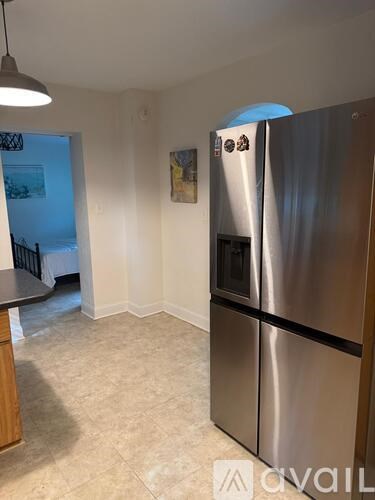 A kitchen with a stainless steel refrigerator and a dining table.