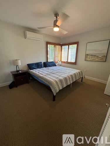 A bedroom with a bed, a ceiling fan, and a window with blinds.