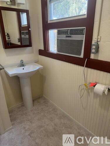 A bathroom with a sink, mirror, and window.