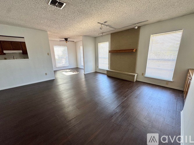 A spacious room with wooden flooring and a ceiling fan.