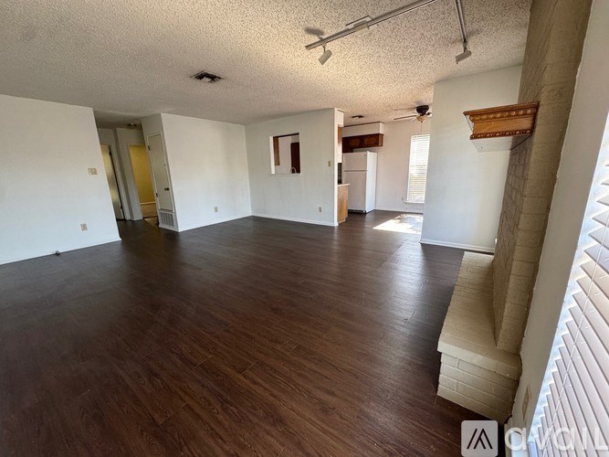 A spacious room with wooden flooring and white walls.