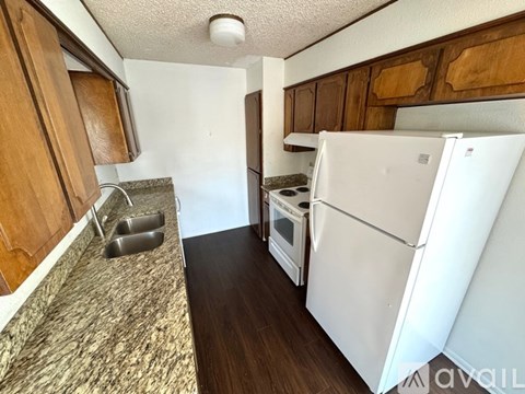A kitchen with a white fridge, stove and wooden cabinets.