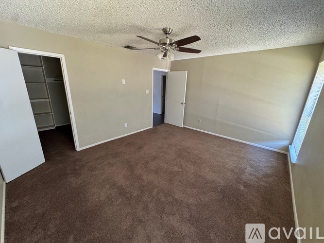 A room with a ceiling fan and carpeted floor.