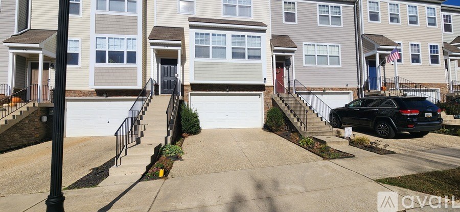 A black car is parked in front of a house with a white garage door.