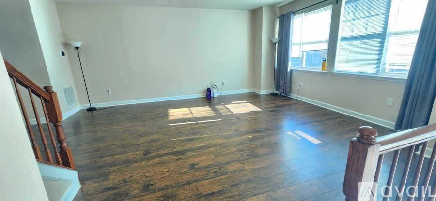A room with wooden floors and a window with curtains.