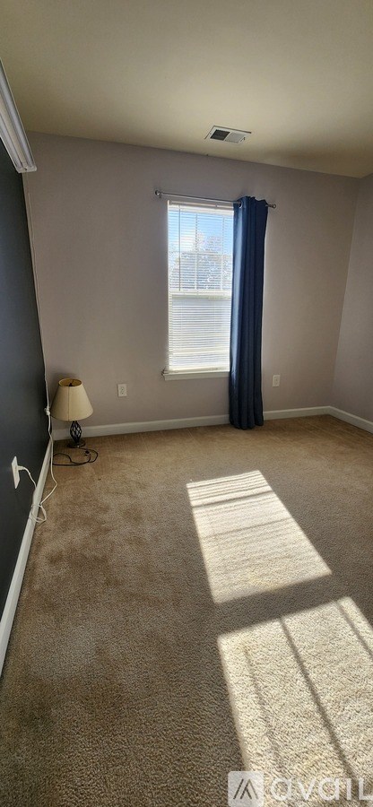 A room with a carpeted floor and a window with blue curtains.