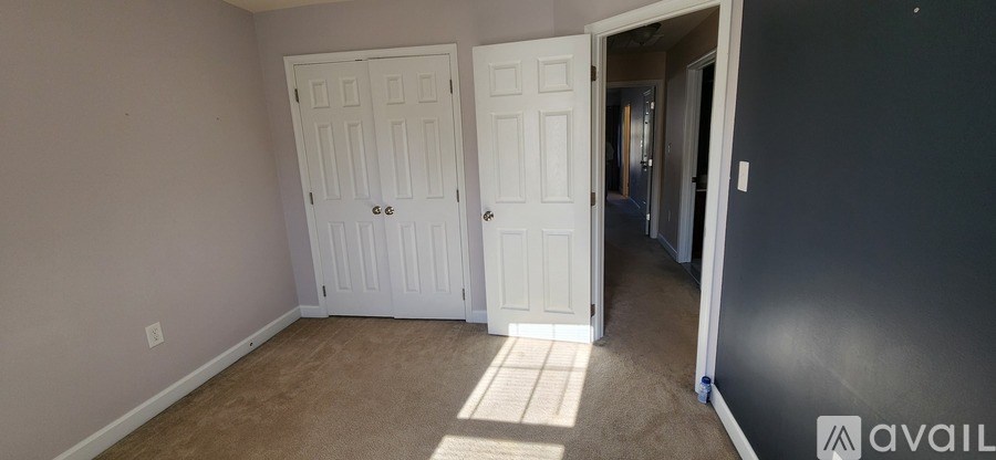 A room with a white door and a carpet on the floor.
