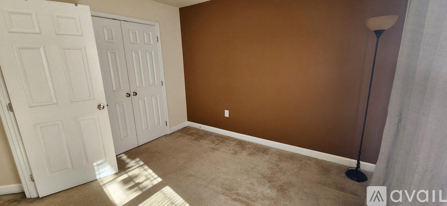A room with brown walls, a white door, and a carpeted floor.