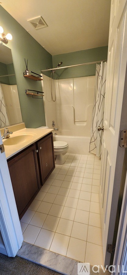A bathroom with a green wall and white tiles.