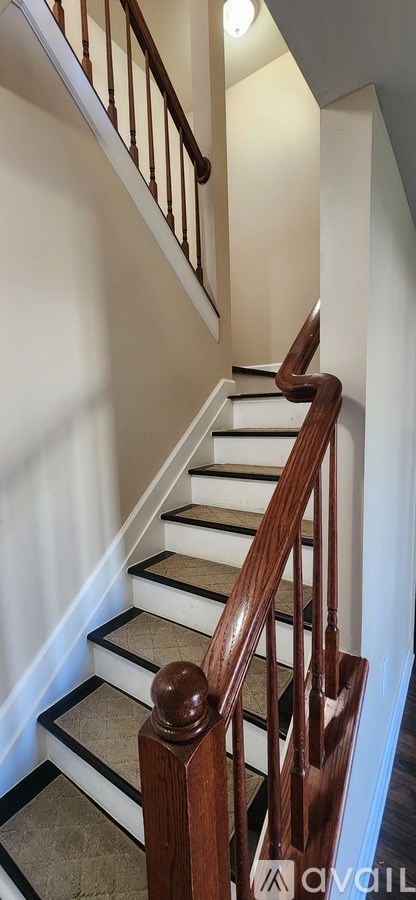 A staircase with a wooden handrail and white steps.