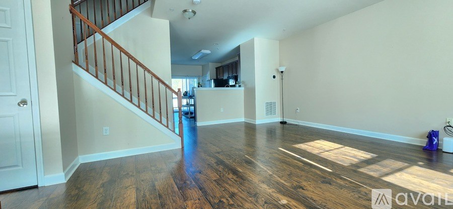 A spacious living room with wood flooring and a staircase leading to the upper level.