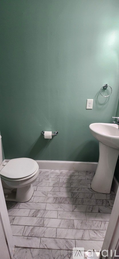A white toilet sits next to a white sink in a bathroom.
