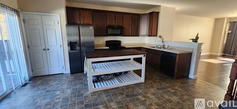 A kitchen with a refrigerator, sink, and a dining table with chairs.