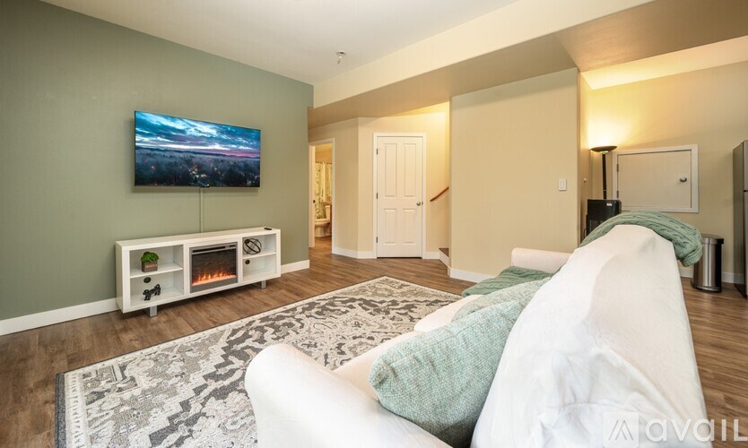 A living room with a white couch and a flat screen TV mounted on the wall.