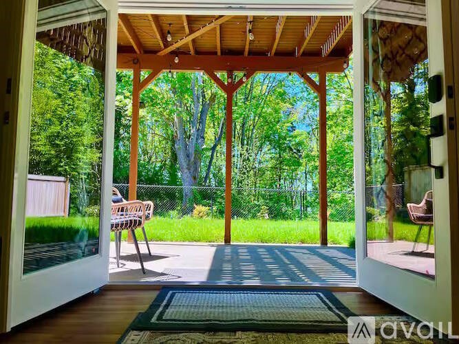 A wooden covered porch with a bench and a rug.
