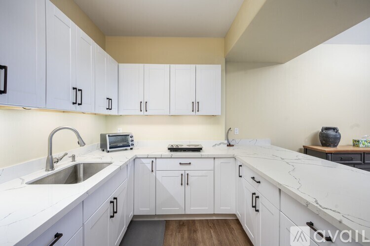 A kitchen with white cabinets and a marble countertop.
