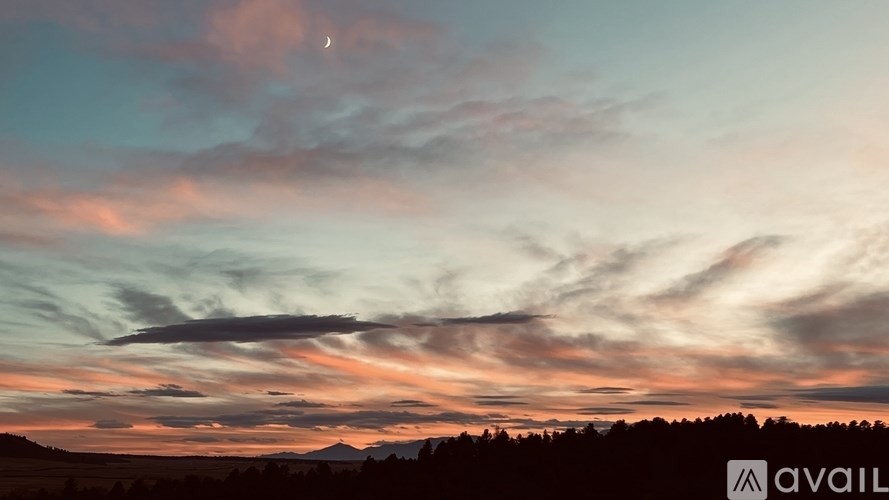 A beautiful sunset with a crescent moon visible in the sky.