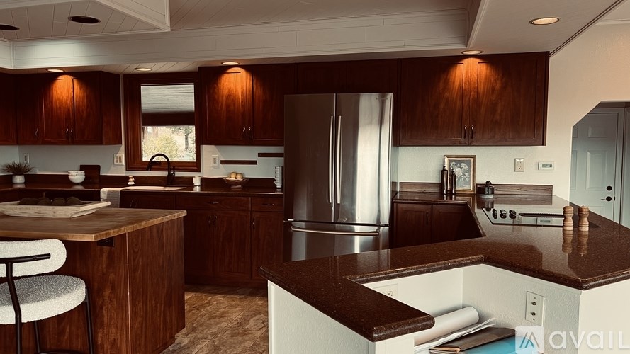 A modern kitchen with wooden cabinets and a stainless steel refrigerator.