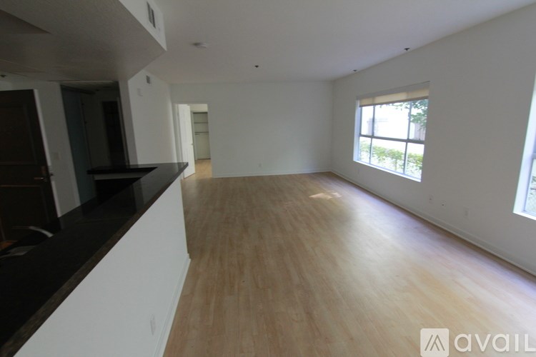 A spacious room with wooden flooring and a large window.