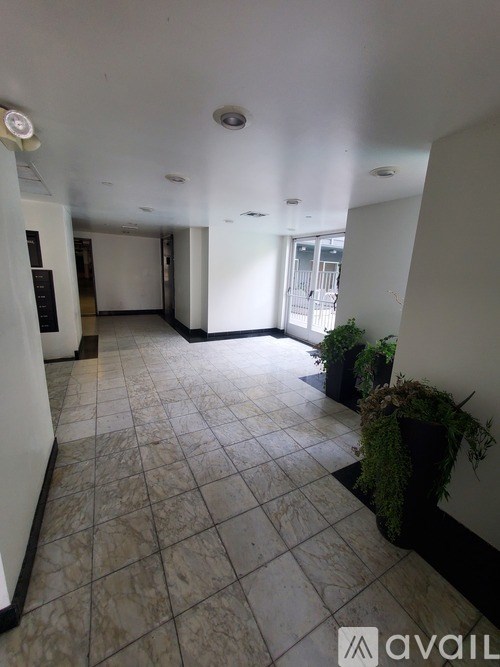 A hallway with tiled floors and a few potted plants.