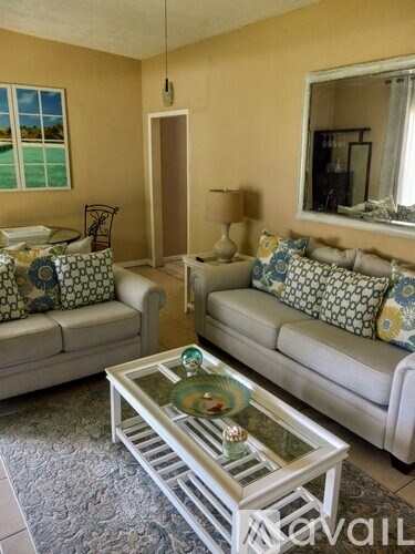 A living room with a white couch, a glass coffee table, and a mirror on the wall.