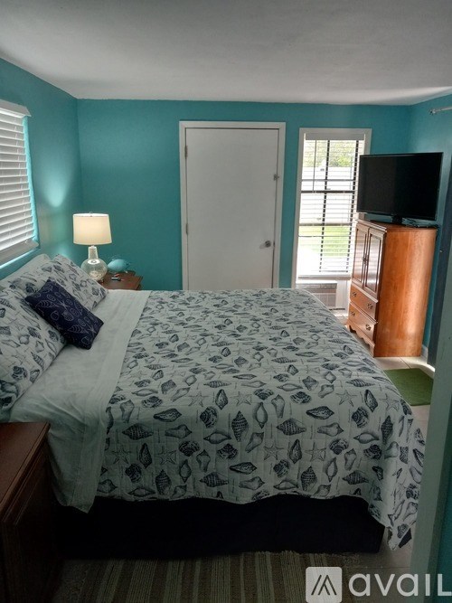 A bedroom with a bed, a lamp, and a television.