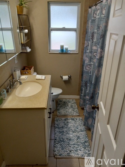 A bathroom with a sink, toilet, and a window.