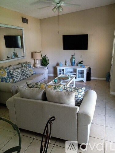 A living room with a white couch and a television mounted on the wall.
