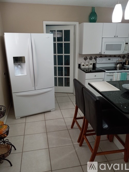 A kitchen with a white fridge and black countertop.