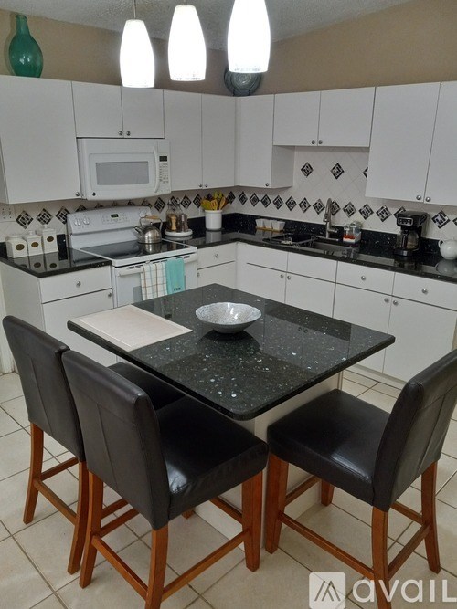 A kitchen with a table and chairs in front of it.