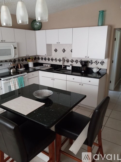 A kitchen with black countertops and white cabinets.