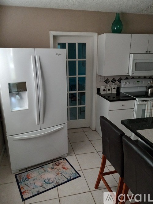 A kitchen with a white fridge and a black counter.