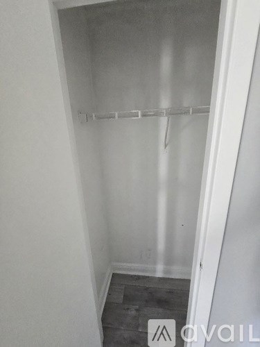 A white closet with a shelf and a door.