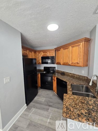 A kitchen with black appliances and wooden cabinets.