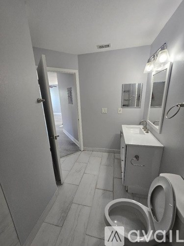 A bathroom with a toilet, sink, and mirror.
