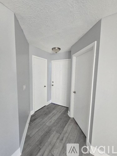 A hallway with two doors and a wooden floor.