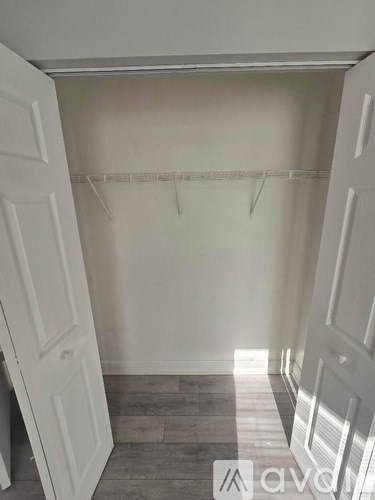 A white closet with a grey floor and a white door.