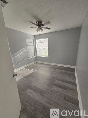 A room with a ceiling fan and wooden flooring.