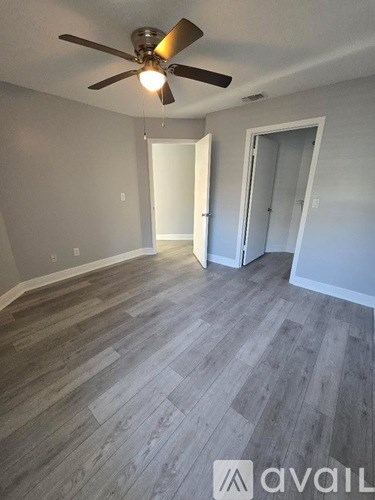 A room with a ceiling fan and wood flooring.
