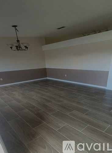 A room with wooden flooring and a chandelier.