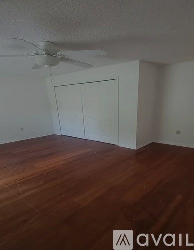 A room with a ceiling fan and wooden floors.