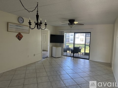 A living room with a chandelier, a ceiling fan, and a large window.