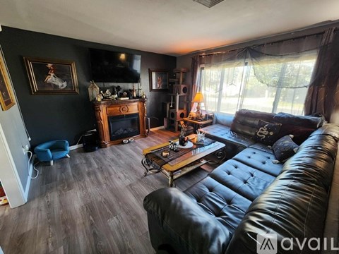 A living room with a black leather couch and a wooden coffee table.
