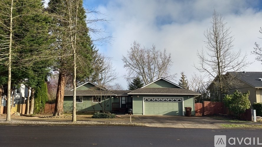 A house with a green garage door is surrounded by trees.