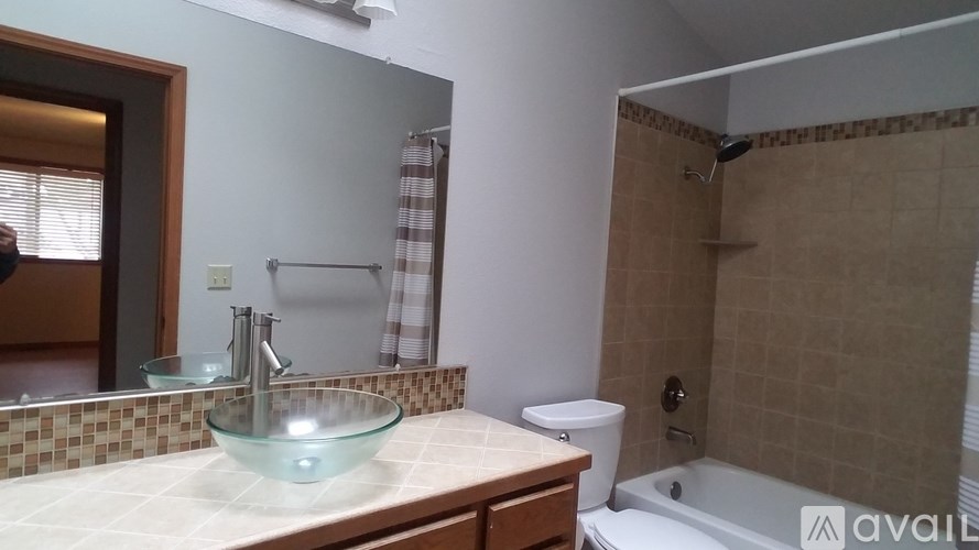 A bathroom with a glass bowl sink and a white bathtub.