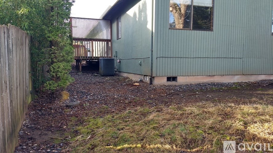 A green building with a window and a door is surrounded by a wooden fence.