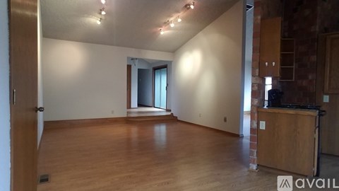 A room with wooden floors and a kitchen area with a stove top oven.